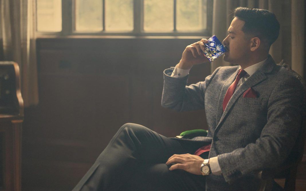 pexels-photo-27972378 a man in a suit and tie drinking from a bottle