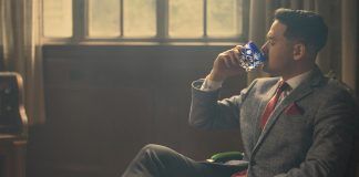a man in a suit and tie drinking from a bottle