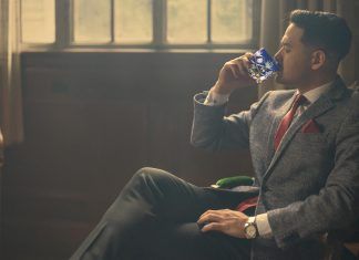 a man in a suit and tie drinking from a bottle