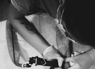 man holding tattoo machine and tattooing person arm