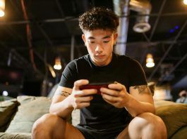 man in black crew neck t shirt playing mobile game