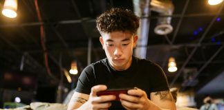 man in black crew neck t shirt playing mobile game