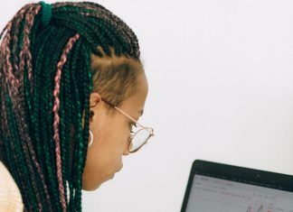woman in a beige jacket analyzing the graph on her laptop