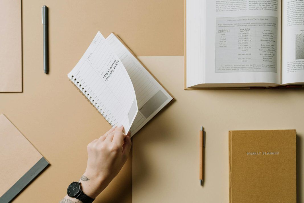 person turning the page of a spiral notebook