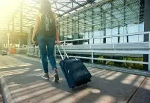 woman walking on pathway while strolling luggage