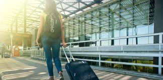 woman walking on pathway while strolling luggage