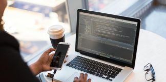 person holding smartphone while using laptop
