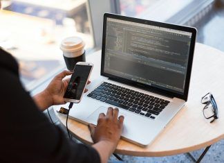 person holding smartphone while using laptop