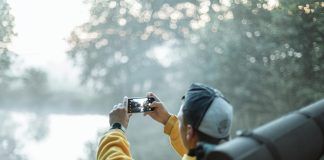 person in yellow jacket taking photo in the forest