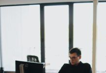 man in black shirt sits behind desk with computers