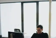 5 AI in Finance Courses for FinTech Analysts Learning Automation, Governance, and Agentic Workflows man in black shirt sits behind desk with computers