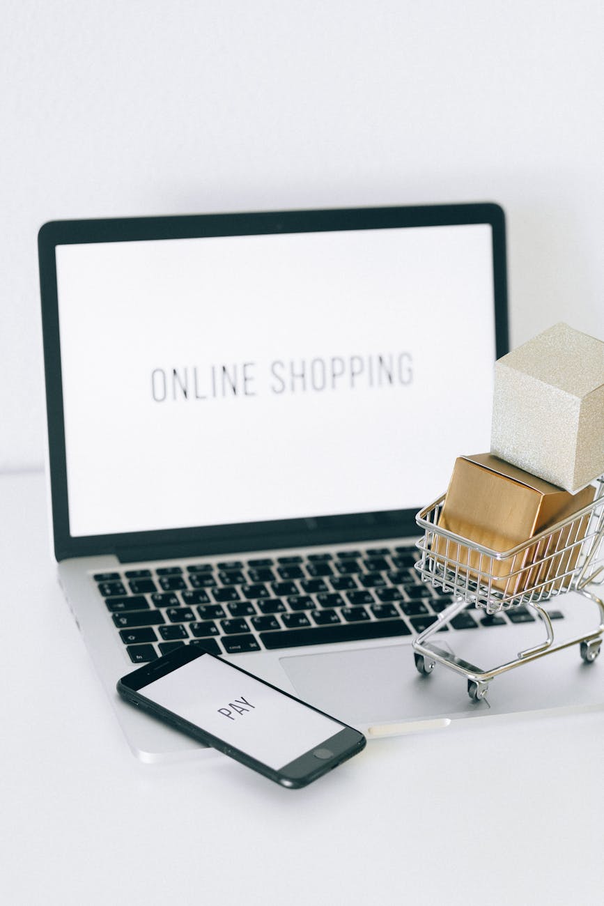 pexels-photo-6214479 a miniature shopping cart and smartphone on macbook laptop