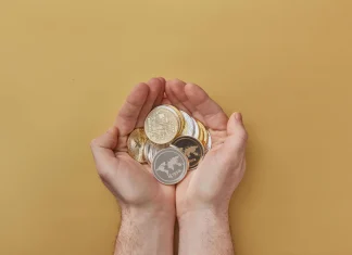 person holding gold and silver round coins